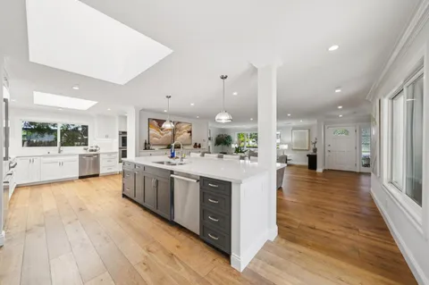 a large kitchen with stainless steel appliances kitchen island granite countertop a large counter top and wooden floors