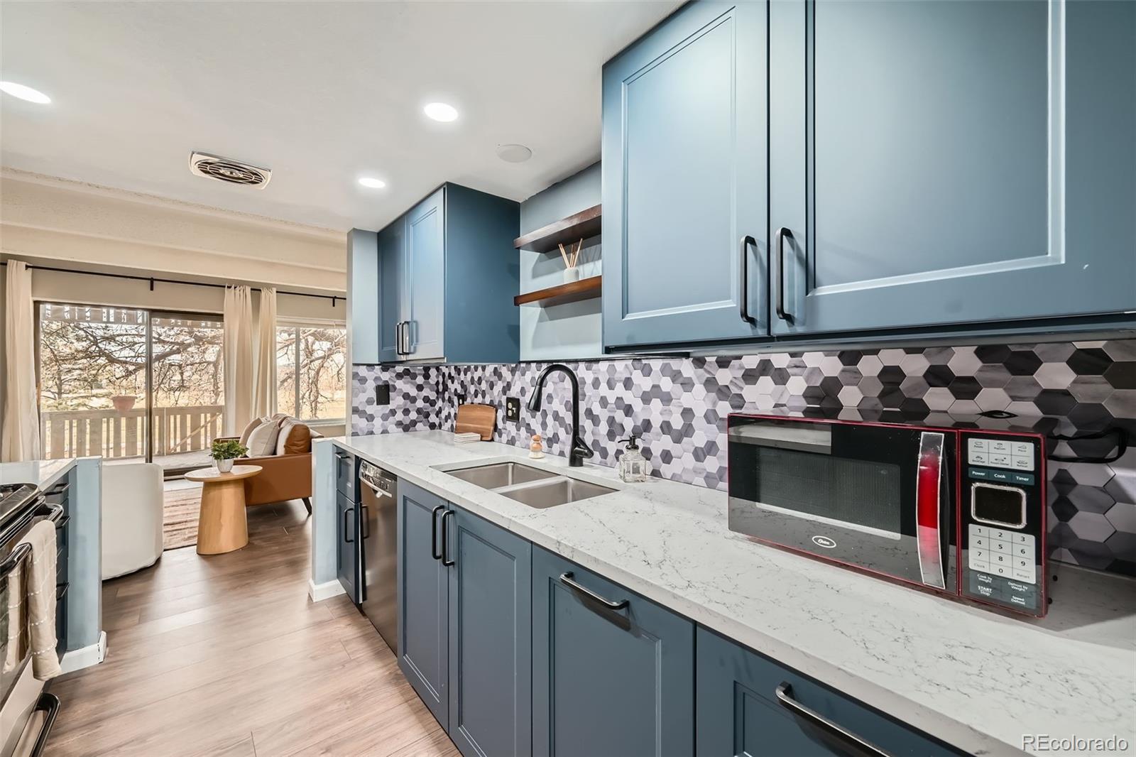 2525 South Dayton Way, Unit 1003 Denver, CO 80231 - Photo 10 of 22 a kitchen with stainless steel appliances sink stove microwave and wooden floor