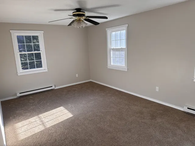 an empty room with windows and fan