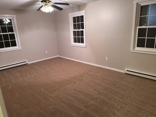 an empty room with windows and fan