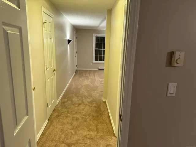 a view of a hallway with wooden floor and a bathroom