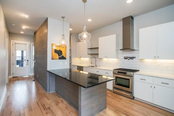 a kitchen with stainless steel appliances granite countertop a sink a stove and a refrigerator