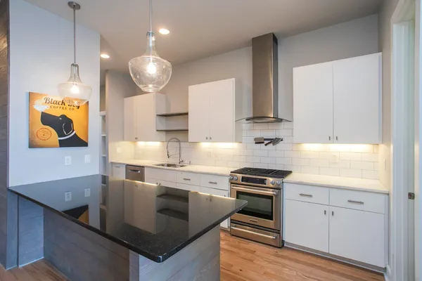 a kitchen with kitchen island granite countertop a sink cabinets and stainless steel appliances