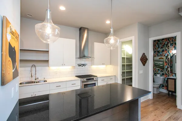 a kitchen with granite countertop a stove a sink and a wooden floor