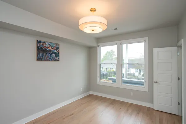 an empty room with wooden floor mirror and windows