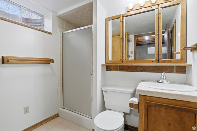 2348 North 770 West Clinton, UT 84015 - Photo 15 of 25 Bathroom featuring a corner vanity with a built-in sink, wood-finish cabinetry, and a mirrored medicine cabinet