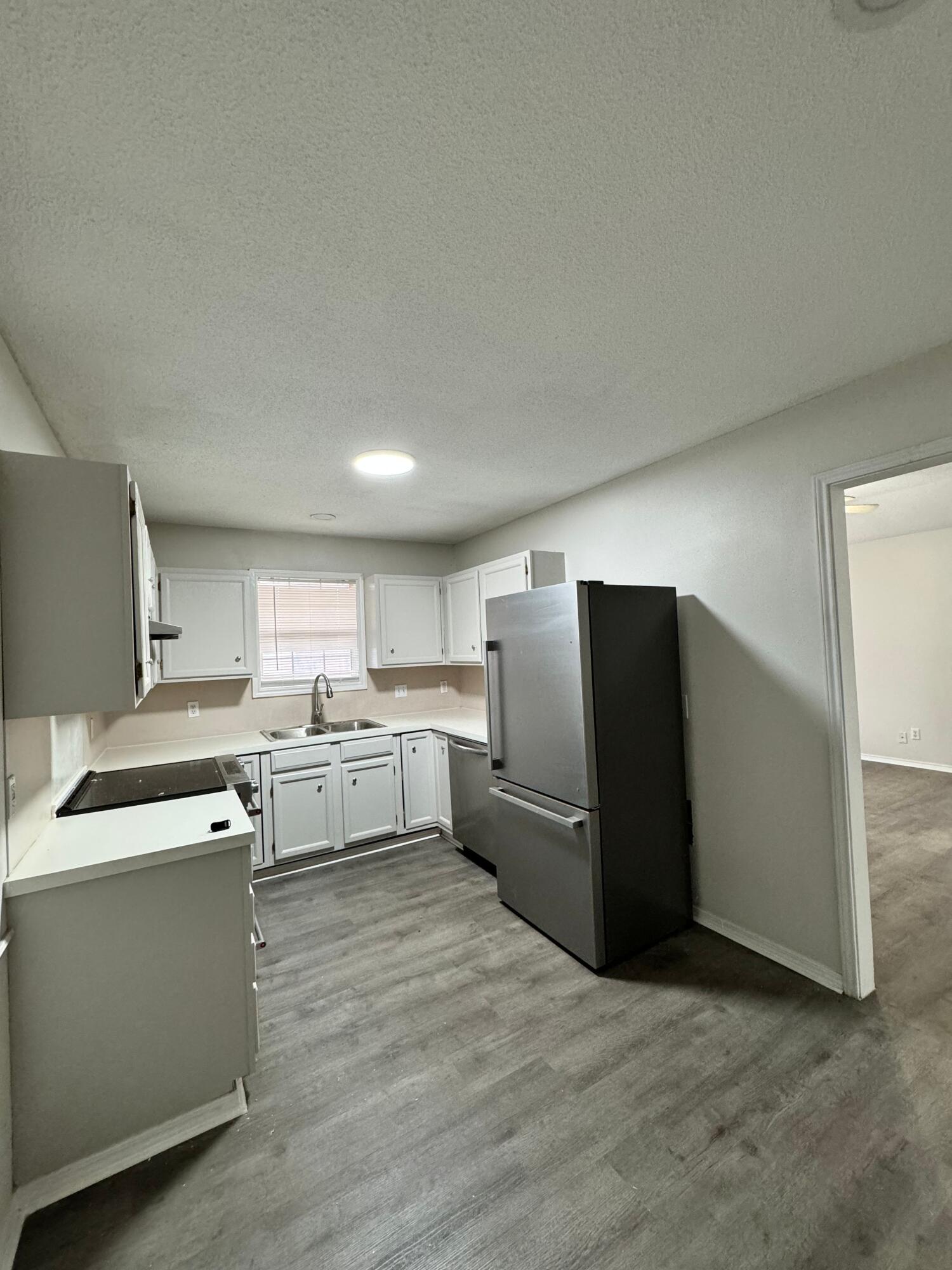 4411-2 Kemper Street Lubbock, TX 79416 - Photo 4 of 14 a kitchen with a refrigerator sink and wooden cabinets