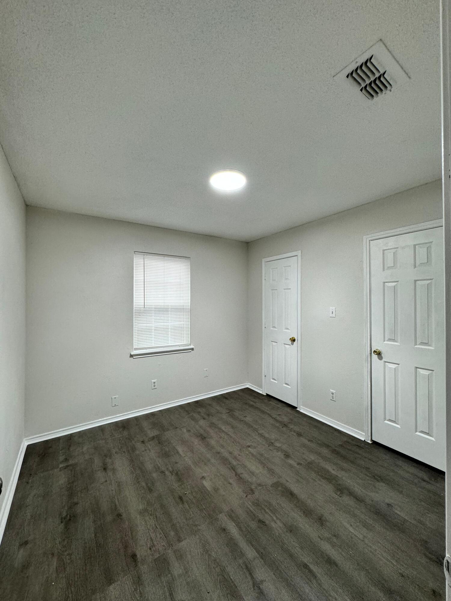 4411-2 Kemper Street Lubbock, TX 79416 - Photo 7 of 14 an empty room with wooden floor and windows