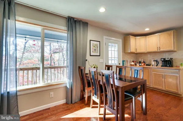 a open dining room with stainless steel appliances wooden floor a table and chairs