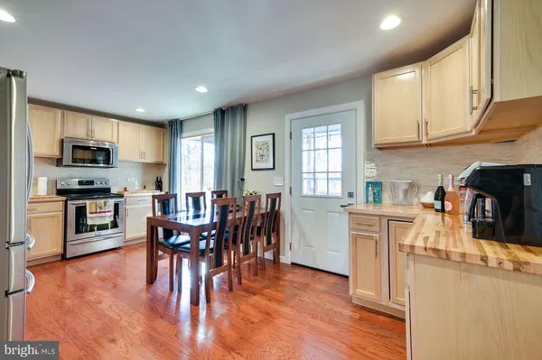 a kitchen with stainless steel appliances granite countertop a stove top oven a sink a dining table and chairs with wooden floor