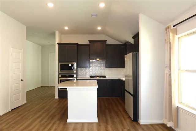 a kitchen with kitchen island granite countertop wooden floors and stainless steel appliances