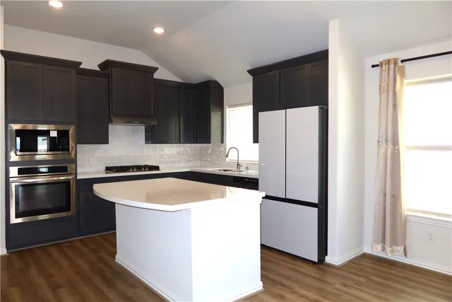 a kitchen with stainless steel appliances granite countertop a refrigerator a sink a stove a microwave and cabinets