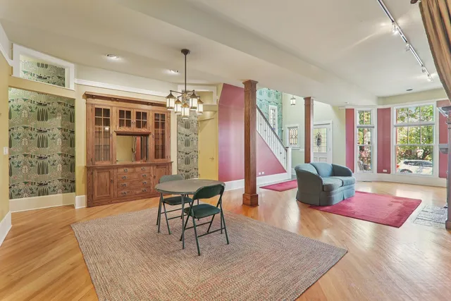 a dining room with wooden floor a chandelier a glass table and chairs