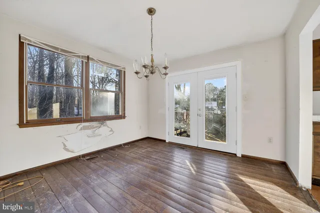 a view of an empty room with window and wooden floor
