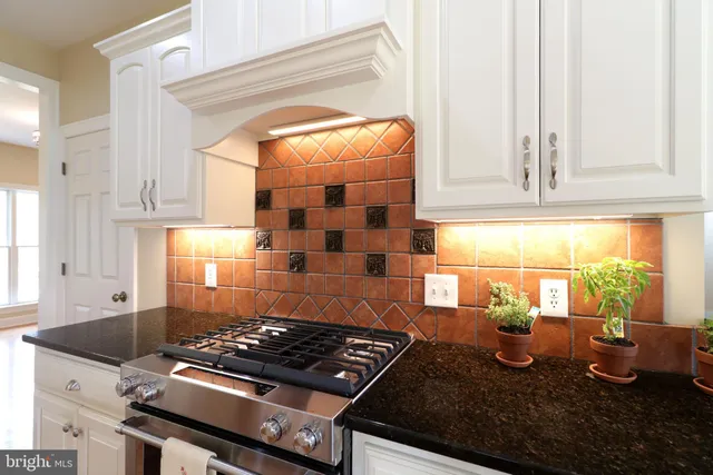 a kitchen with granite countertop a stove and a white cabinet