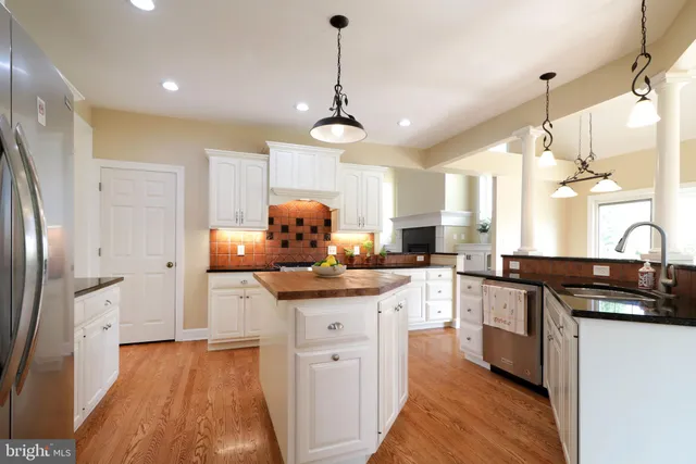 a kitchen with stainless steel appliances granite countertop a sink a stove a refrigerator and island with wooden floor