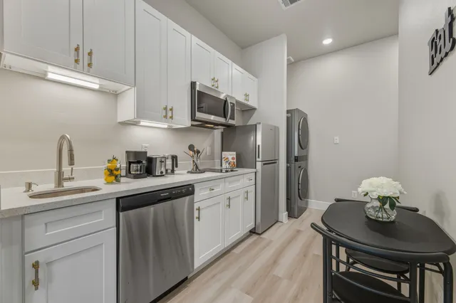a kitchen with stainless steel appliances kitchen island granite countertop a sink cabinets and wooden floor