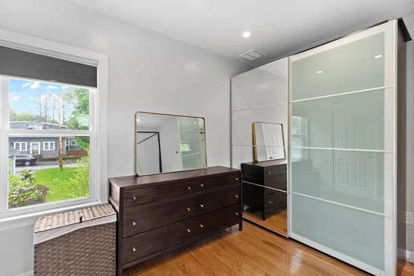 a room with a dresser mirror and a window