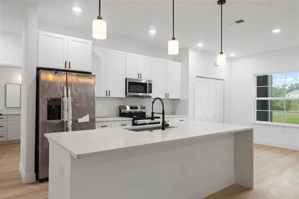 a kitchen with kitchen island a sink stainless steel appliances and refrigerator