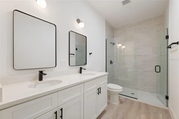 a bathroom with a double vanity sink toilet mirror and shower