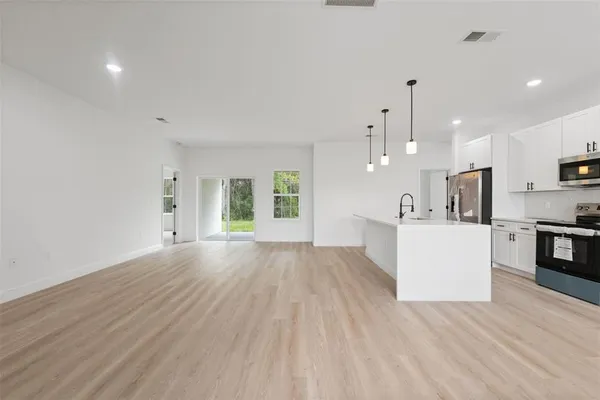 a view of a kitchen with cabinets stainless steel appliances a sink and a window