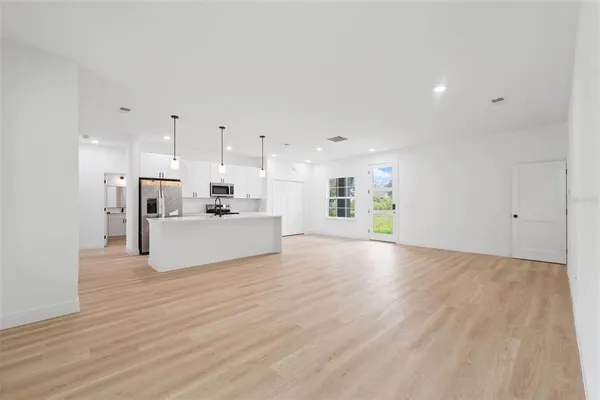 a view of a kitchen with kitchen island a sink wooden floor and a refrigerator