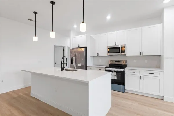 a kitchen with kitchen island a sink stainless steel appliances and white cabinets