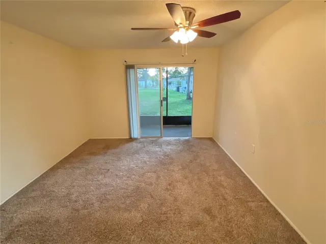 an empty room with a chandelier fan and windows