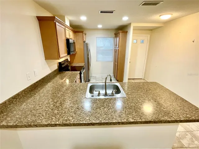 a kitchen with kitchen island granite countertop a sink a counter top space and cabinets
