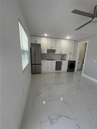 a living room with stainless steel appliances kitchen island granite countertop a refrigerator and a sink