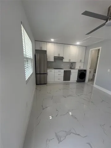 a living room with stainless steel appliances kitchen island granite countertop a refrigerator and a sink