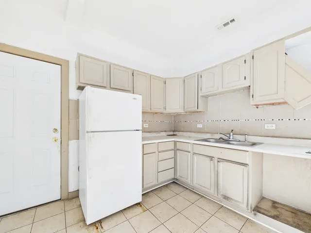 a kitchen with white cabinets and white refrigerator