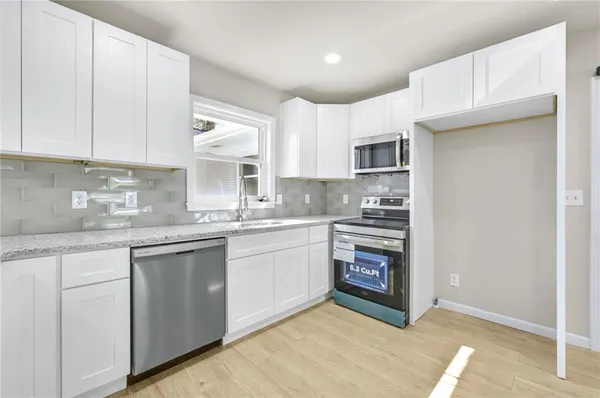 a kitchen with cabinets appliances a sink and a window