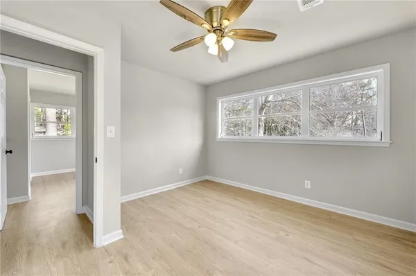 an empty room with wooden floor chandelier fan and windows