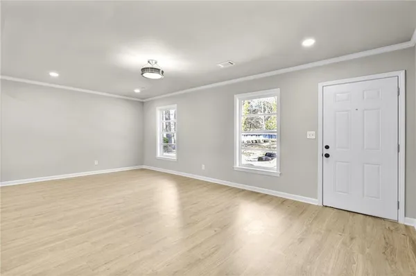 a view of an empty room with a window and wooden floor