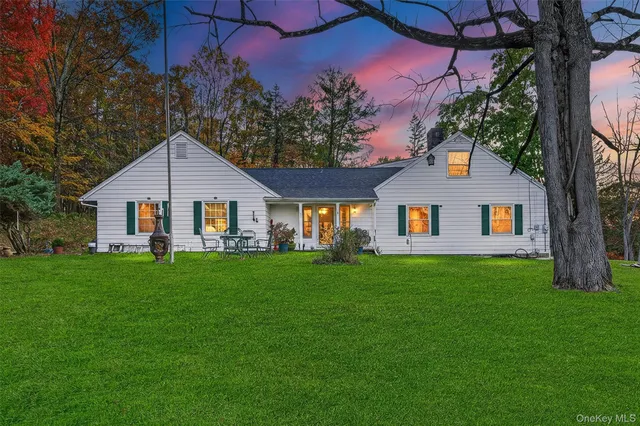 a view of a yard in front of a house with plants and large tree