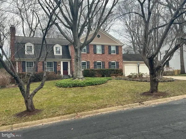 a front view of a house with a yard and large trees