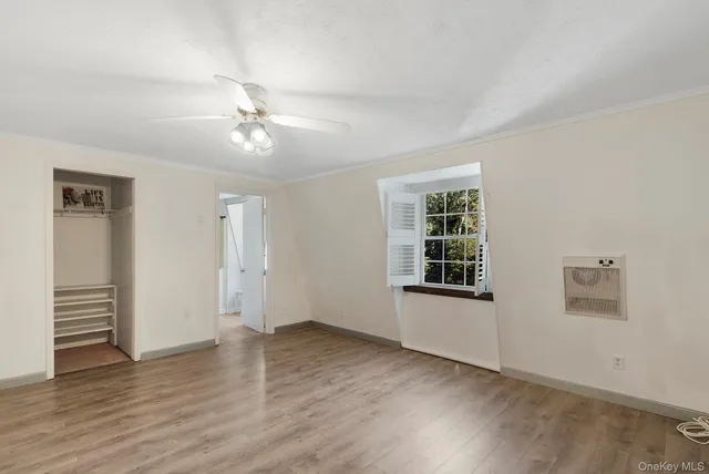 an empty room with wooden floor chandelier fan and windows