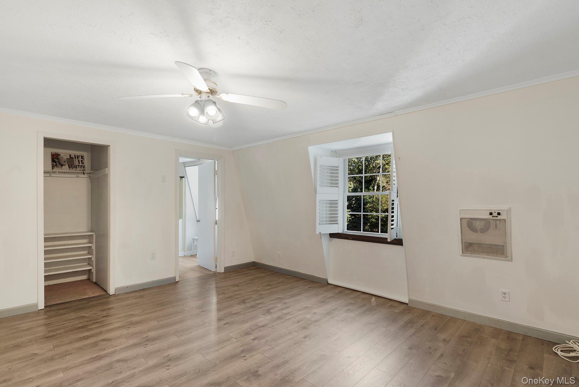 18 Glade Road Springs, NY 11937 - Photo 9 of 12 an empty room with wooden floor chandelier fan and windows
