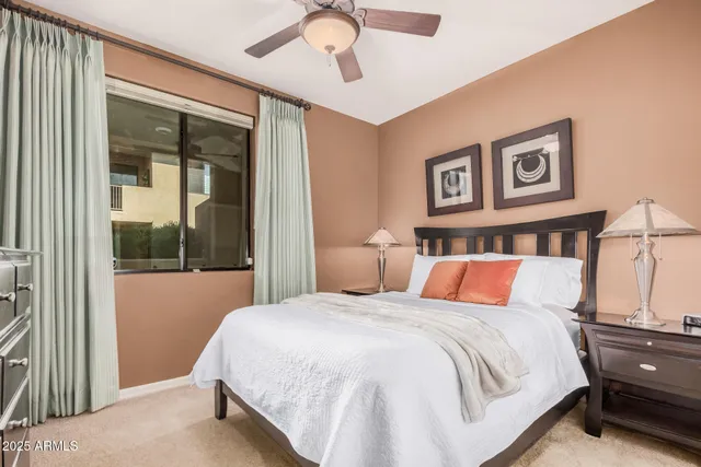 a bedroom with a large bed and a chandelier fan