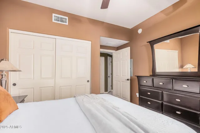 a bedroom with a bed and a mirror on the dresser