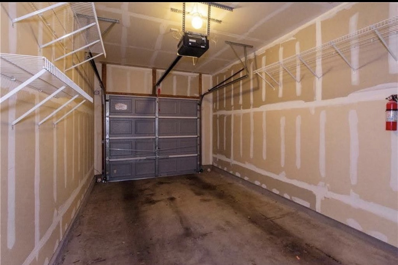 1900 Scofield Ridge Parkway, Unit 3101 Austin, TX 78727 - Photo 22 of 24 Single-car garage featuring a paneled overhead door, concrete flooring, overhead lighting, and built-in wire shelving