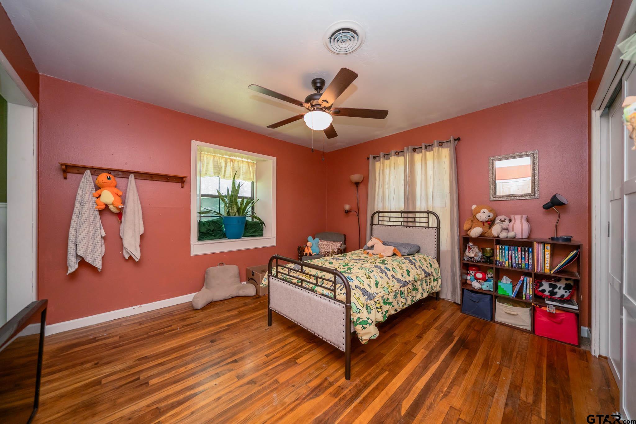 141 Cedar Street Rusk, TX 75785 - Photo 37 of 44 a bedroom with a bed and a bookshelf with wooden floor
