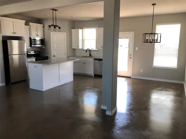 a kitchen with stainless steel appliances kitchen island wooden floors cabinets and a window