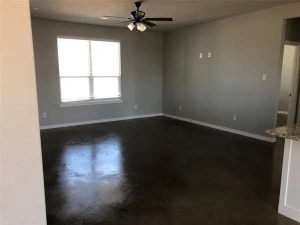 an empty room with wooden floor fan and windows