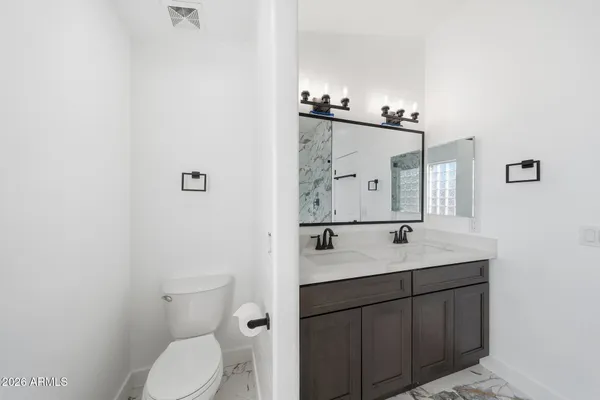 a bathroom with a granite countertop sink mirror vanity and toilet