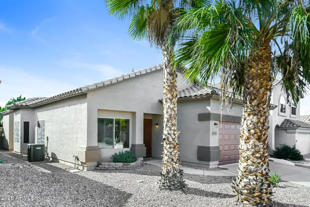 a front view of a house with garden and trees