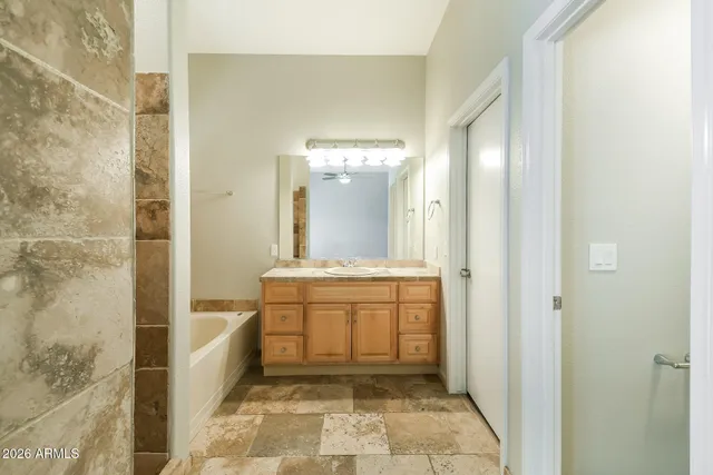 a bathroom with a granite countertop sink a mirror and a bathtub