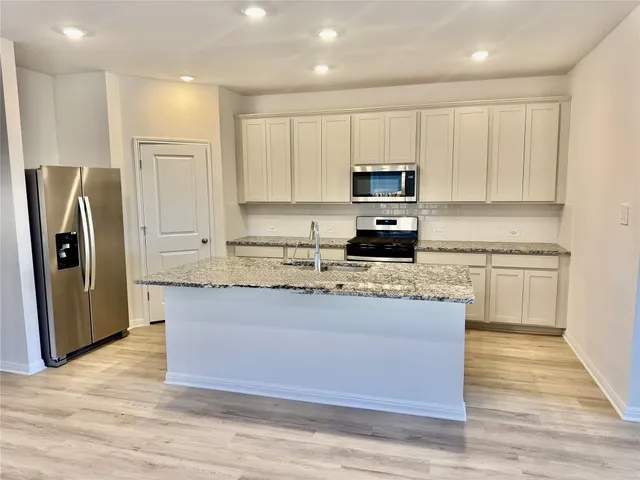 a kitchen with granite countertop a refrigerator and a stove top oven