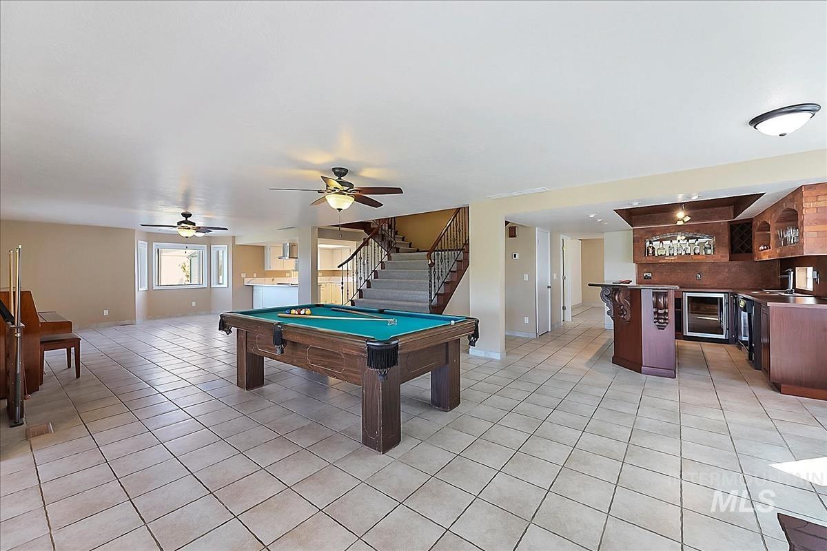 2804 West Sunrise Rim Road Boise, ID 83705 - Photo 14 of 50 Spacious entertainment area featuring a billiards table, tile flooring, ceiling fans, a staircase with metal railings, and a built-in wet bar with cabinetry and integrated appliances
